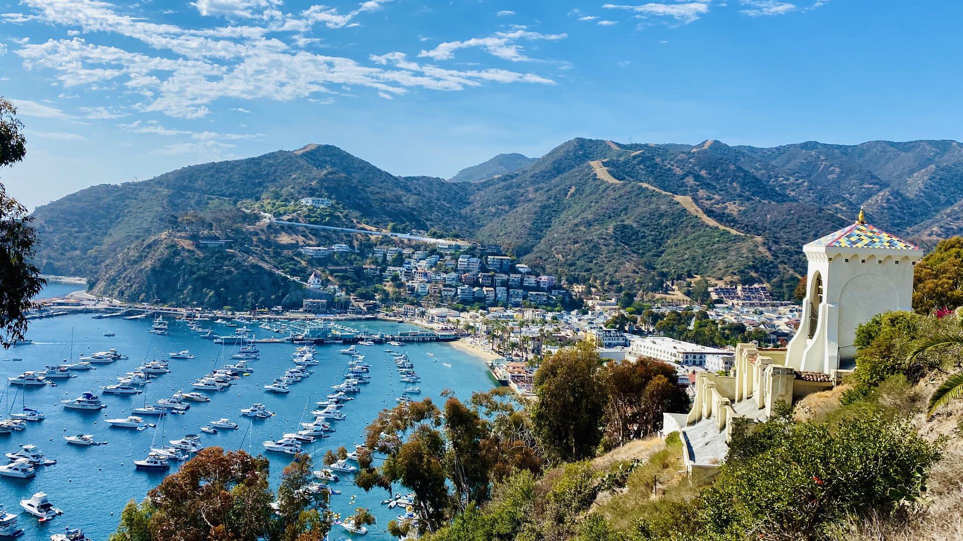 A far view of Catalina Island with water and boats, mountains, and a resort