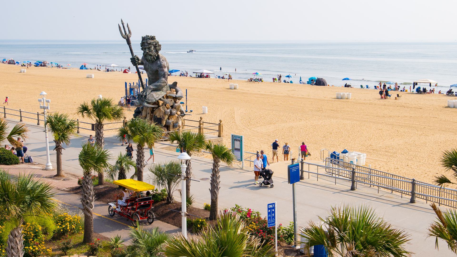 a photo of a beach with a walkway and statue with a trident