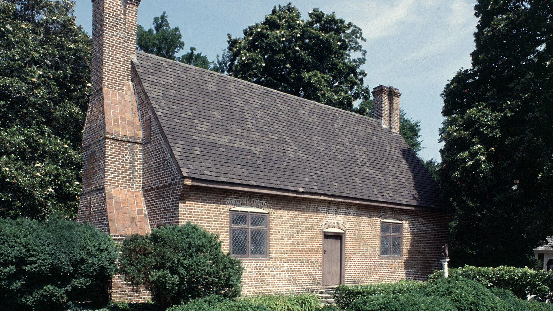 an old brick house surrounded by greenery