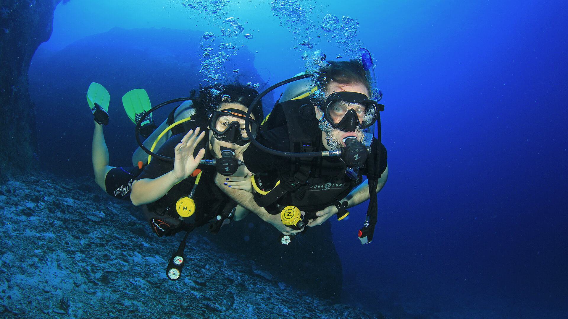 two scuba divers underwater holding each other