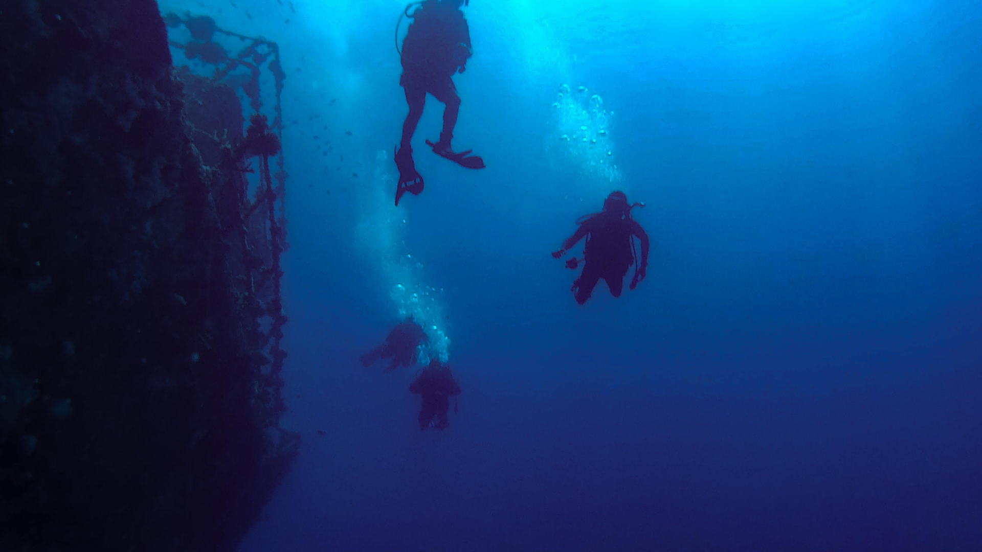 Photo of scuba divers by shipwreck.