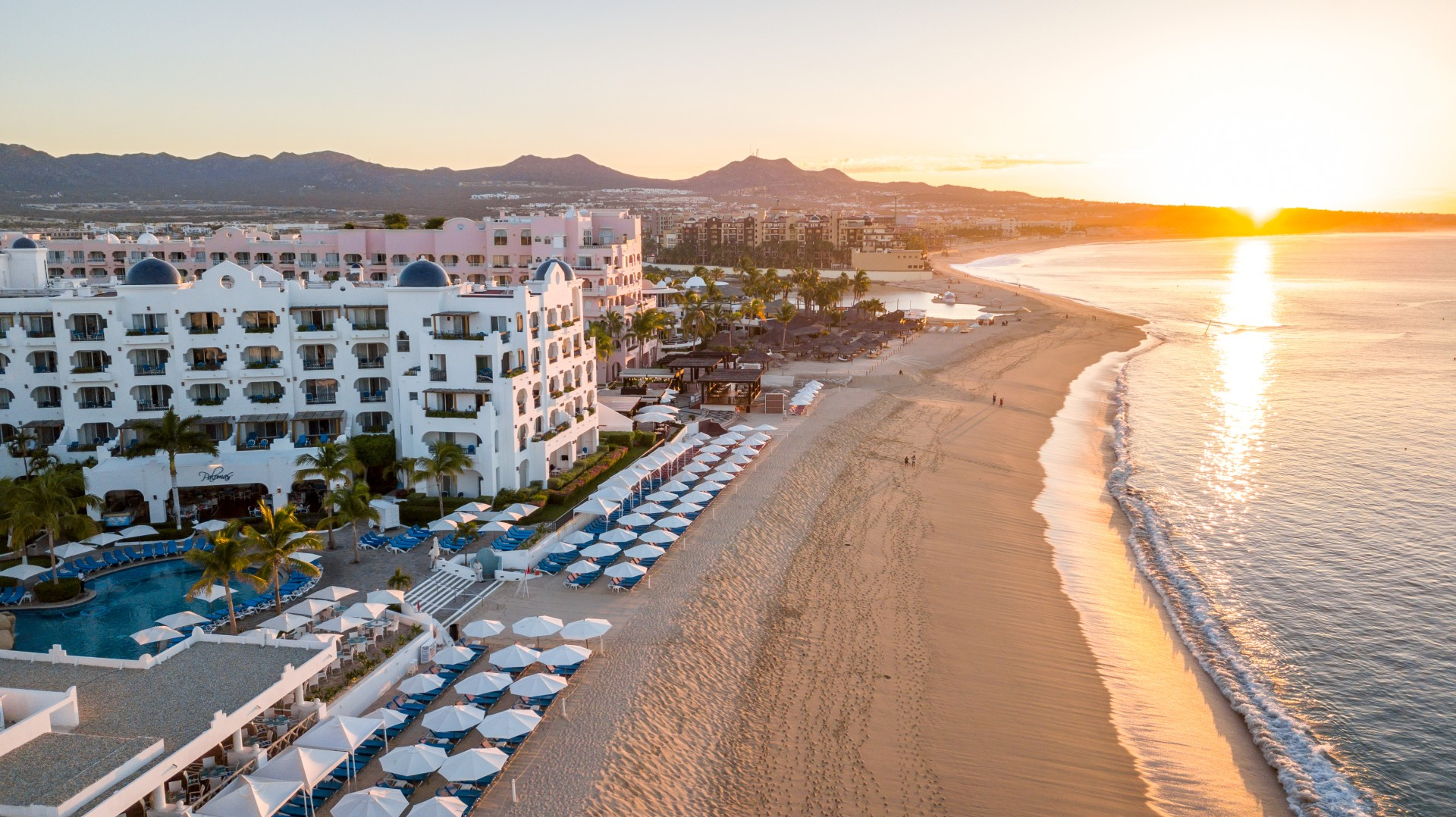 a view of a resort on a beach at sunset
