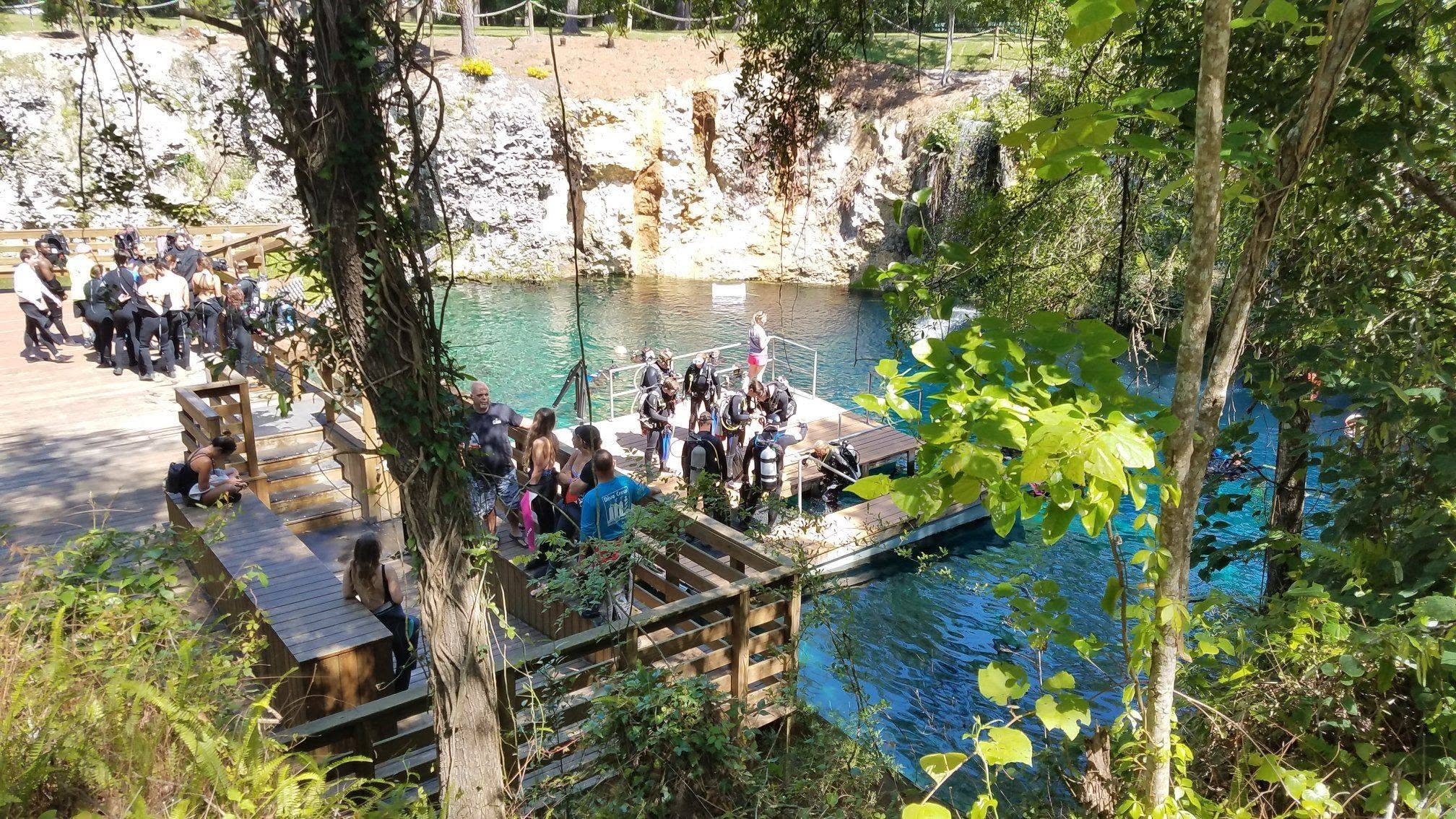 a view of people and divers on a dock by a spring