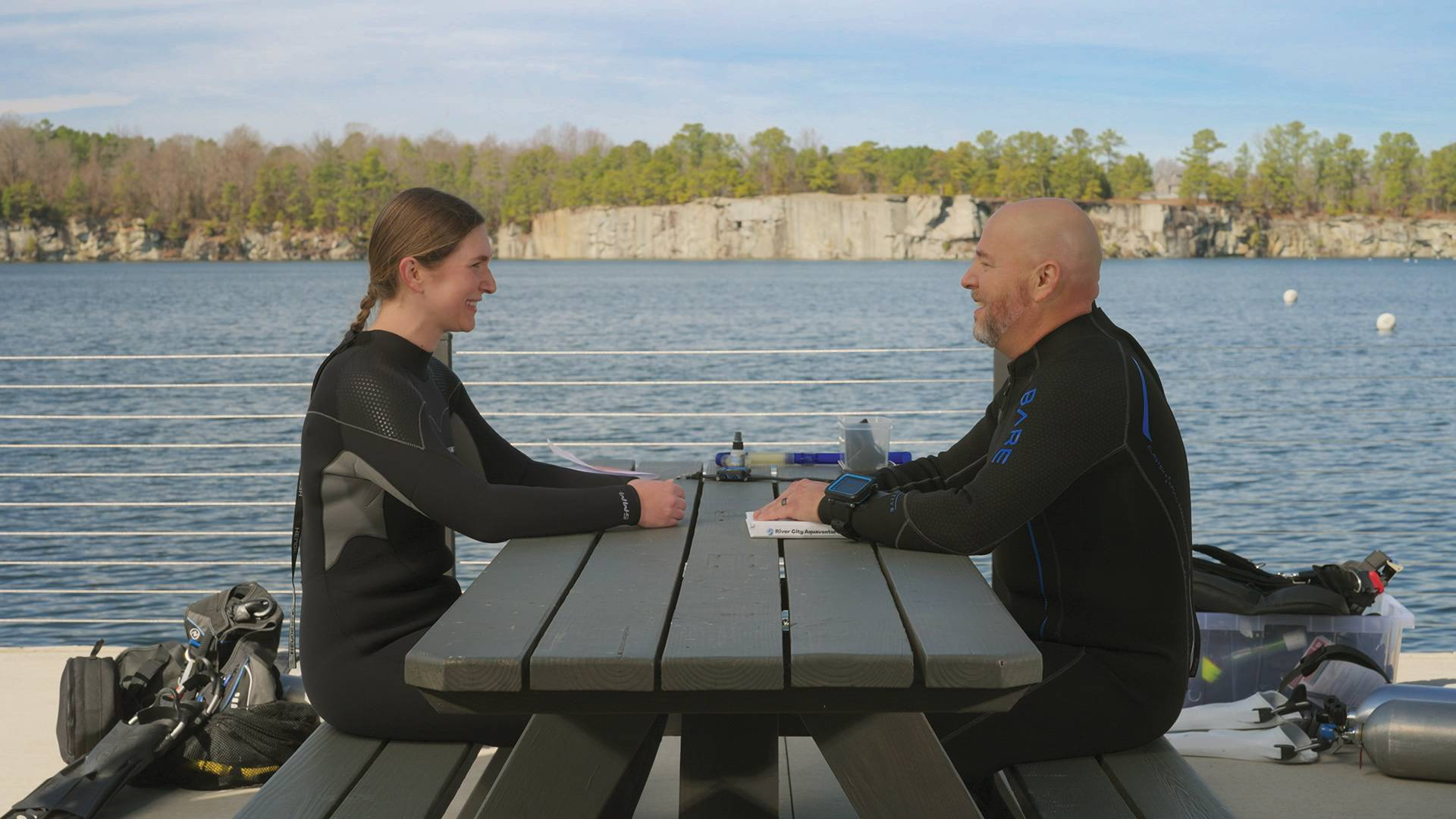 two scuba divers talking at a picnic table